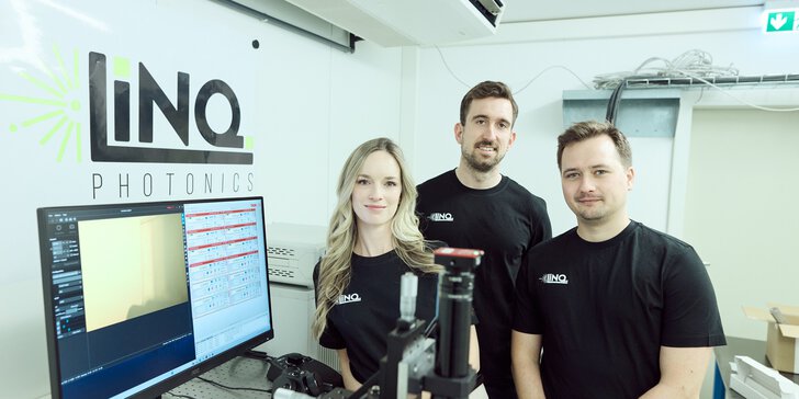 Drei Mitarbeitende von LINQ Photonics stehen in einem modernen Labor neben einem Monitor und optischen Messgeräten. Im Hintergrund ist das Firmenlogo an der Wand zu sehen.
