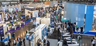 Bird's eye view of Hall A1 at the World of Quantum, with many modern exhibition stands and visitors.