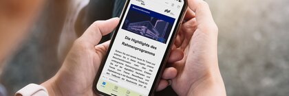 Eine Person hält ein Smartphone in den Händen, auf der die deutschsprachige Seite der Besucherinformationen geöffnet ist.