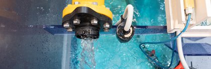 Draufsicht auf eine gelbe Pumpe, die Wasser in ein blaues Becken mit Glaswänden pumpt.