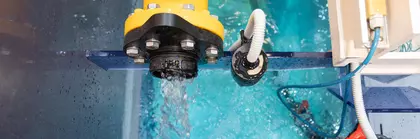 Draufsicht auf eine gelbe Pumpe, die Wasser in ein blaues Becken mit Glaswänden pumpt.