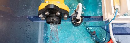 Top view of a yellow pump pumping water into a blue basin with glass walls.
