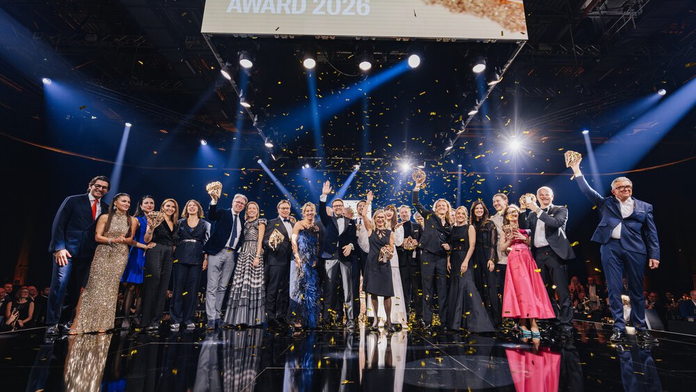 The winners of the INHORGENTA AWARD 2026, dressed in their festive attire, stand on a stage waving to the audience as golden confetti rains down.