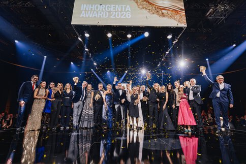 Die festlich gekleideten Gewinner des INHORGENTA AWARD 2026 stehen auf einer Bühne winken ins Publikum, während goldenes Konfetti herab rieselt.
