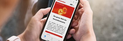 Person hält ein Smartphone, auf dem ceramitec Besucherinformationen über die Welt der Keramikindustrie angezeigt werden.