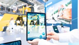Person holding up a tablet for digital representations of a construction site at Hexagon's stand at bauma 2022