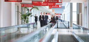 A group of people walk along the express conveyor belts between the exhibition halls.