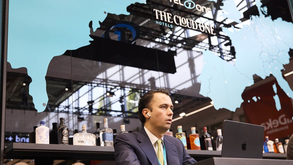 A man is working on his laptop at the Motel One exhibition stand.