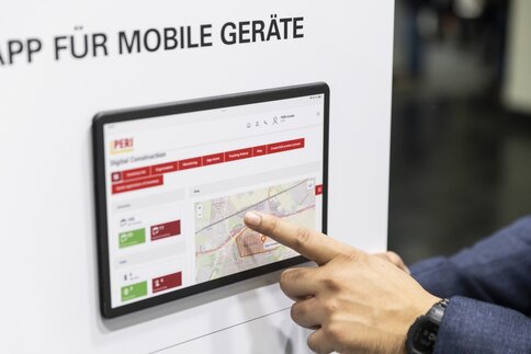 A finger points to a wall-mounted control display.