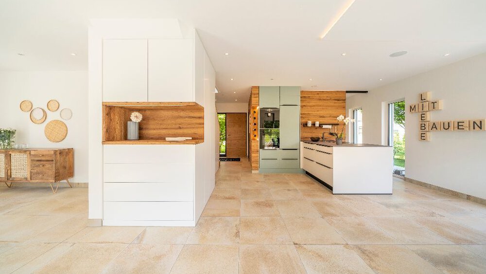 Geräumige, moderne Küche mit weißen Schränken, Holzakzenten und einer großen Kochinsel. Helles, luftiges und minimalistisches Design.