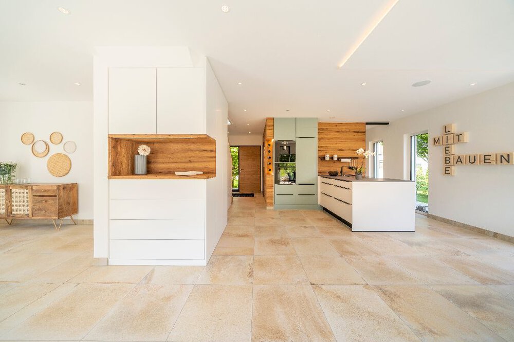 Geräumige, moderne Küche mit weißen Schränken, Holzakzenten und einer großen Kochinsel. Helles, luftiges und minimalistisches Design.