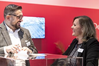 A conversation between a man and a woman in front of a miniature representation of a building