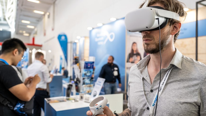 A man with a virtual reality headset tries out a demo at an exhibition stand.