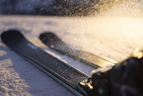 Nahaufnahme der Nordica Belle DC 72-Skier auf Schnee. Das Sonnenlicht wird von den Schneeflocken reflektiert und erzeugt einen glitzernden Effekt.