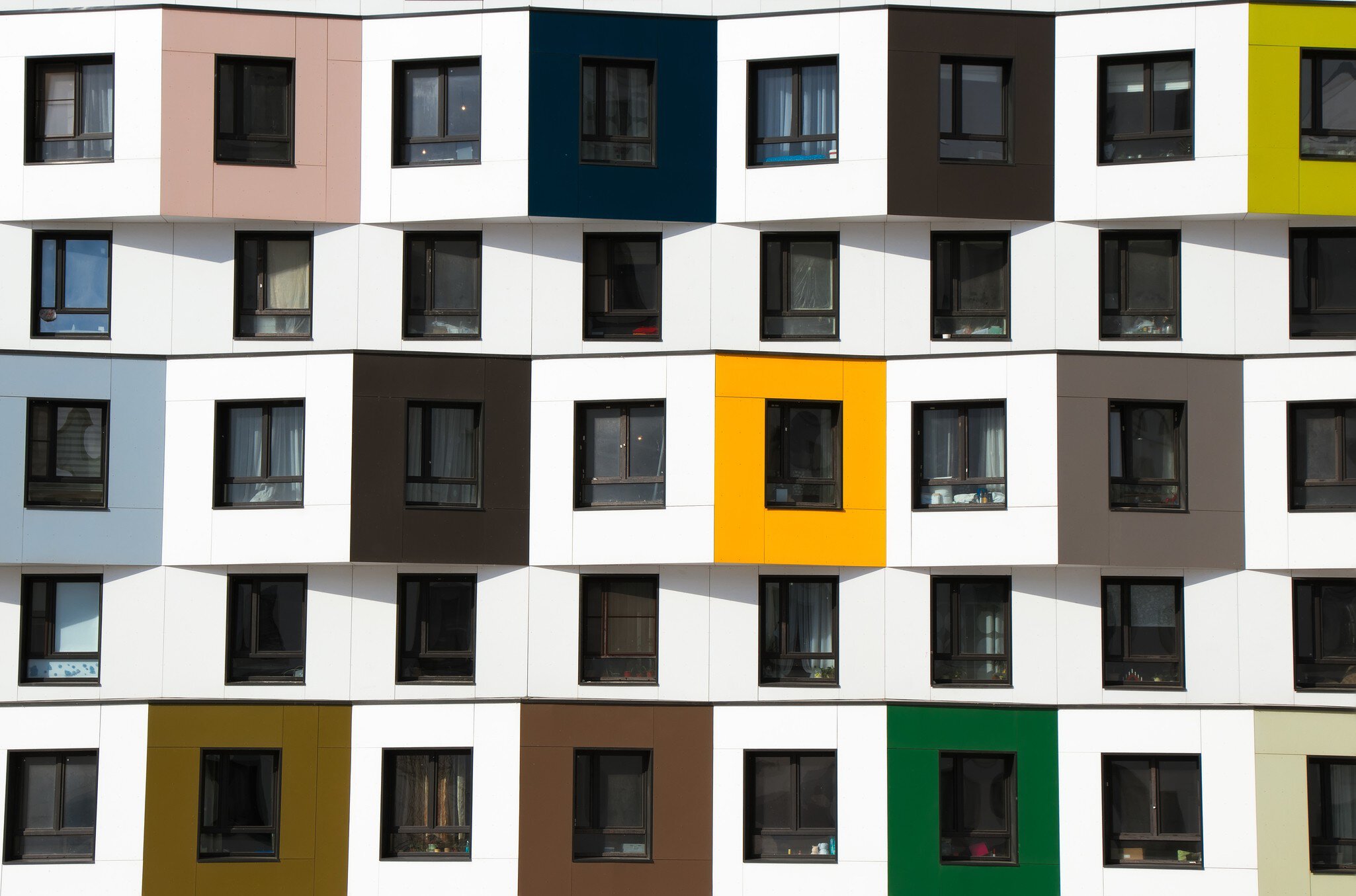 Nahaufnahme einer farbenfrohen geometrischen Hausfassade mit zahlreichen Fenstern.