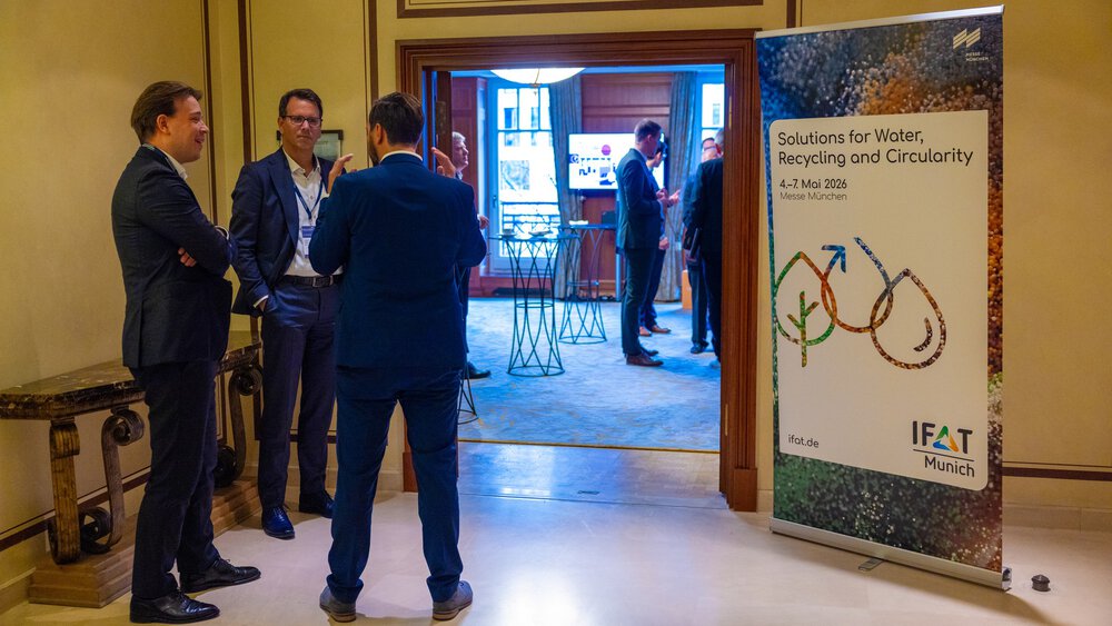 Eingangsbereich eines Veranstaltungsraums mit Gesprächen; rechts steht ein IFAT Munich-Banner, im Hintergrund ist der Raum mit Stehtischen zu sehen. 