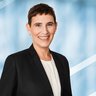 Portrait einer lächelnden Frau mit kurzen Haaren in schwarzem Blazer und weißer Bluse.