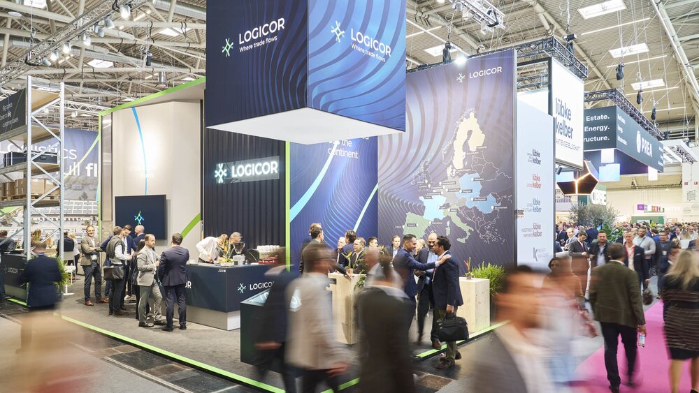 Der Eckstand von LOGICOR auf der EXPO REAL mit riesigen Werbebannern und zahlreichen interessierten Besuchern.