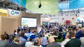 Fachbesucher sitzen in bunten Sesseln am Stand des BDE und verfolgen eine Präsentation auf einer großen Leinwand.