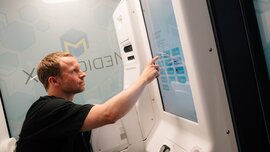 Besucher bedient ein digitales Terminal oder Selbstbedienungssystem an einem DMEA-Messestand