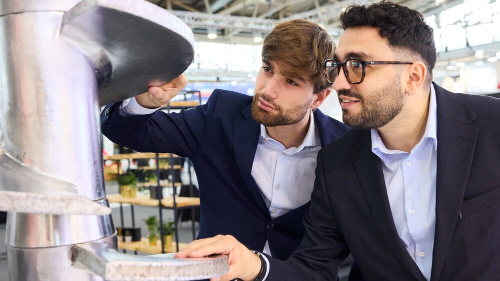 Two men are inspecting a large metal structure