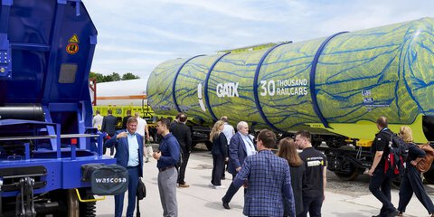 Visitors walk between containers and freight trains across the outdoor exhibition area.