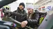 Two people stand at a bicycle stand and take a closer look at a bicycle.