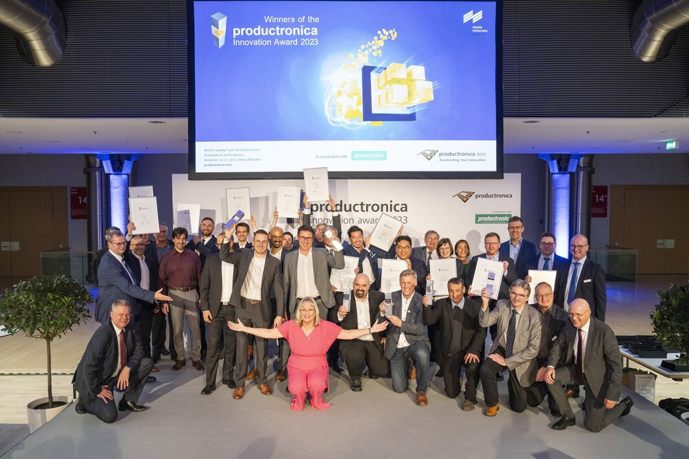 Die zahlreichen Gewinner des productronica Innovation Award 2023 posieren gemeinsam kniend und stehend mit ihren Preisen und Urkunden für ein Gruppenfoto.