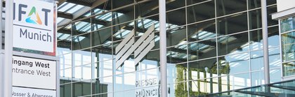 Nahansicht vom Eingangsbereich West der Messe München während der IFAT von der spiegelnden Glasfassade und dem Logo der Messe München.