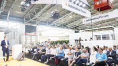 A speaker addresses a packed audience on the stage of the automatica Forum in Hall A5.