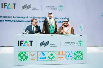 Three men signing a contract with IFAT and Messe München banners, logos and a decorative table.