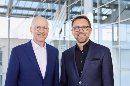 Die CEO-Doppelspitze der Messe München ist auf einem gut beleuchteten Bild mit einem Gebäude im Hintergrund abgebildet zu sehen.