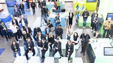 Der Messestand der Firma Holcim ist von oben zu sehen. Besucher auf dem Messestand schauen zusammen auf einen großen Screen.