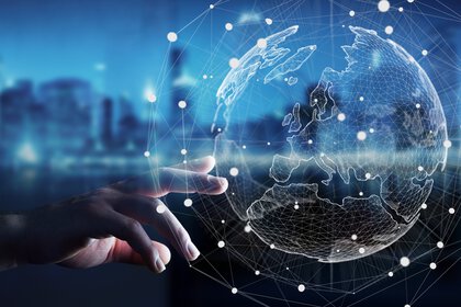 A hand reaches out to a digital globe with networked nodes and lines symbolising global connectivity.