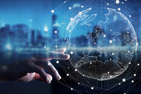 A hand reaches out to a digital globe with networked nodes and lines symbolising global connectivity.
