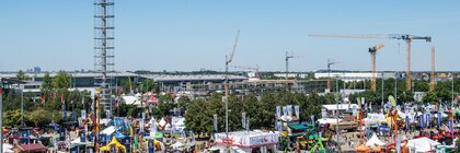 Luftaufnahme des Freigeländes der Messe München während der INTERFORST, Blick auf den Messeturm, Stände, Pavillons, Forstmaschinen und Baukräne.