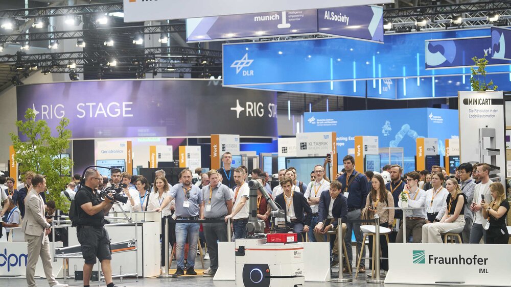 A crowd watches a robotics demonstration at an exhibition booth.