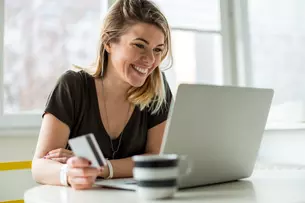 Frau vor einem Laptop mit Kreditkarte in der Hand