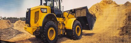 A yellow CAT wheel loader with front shovel operates between piles of earth and building materials.