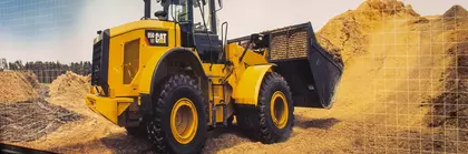 Ein gelber CAT Radlader mit Frontschaufel operiert zwischen Erdhaufen und Baumaterialien.