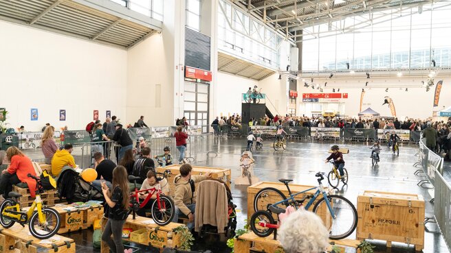 Blick auf Messehalle, in der Kinder Fahrräder ausprobieren können