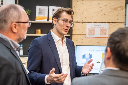 Young man explains something to two other men at the IFAT Munich Startup Area.