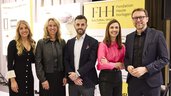 Five people standing in front of a yellow and black banner of the Fondation Haute Horlogerie (FHH) and smiling.