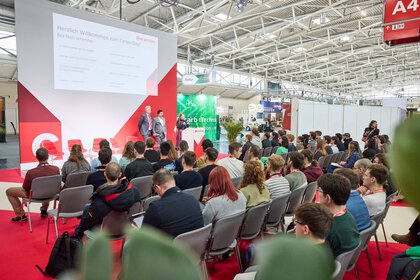 Presentation at the ceramitec CareerDay with a large audience in an exhibition hall.