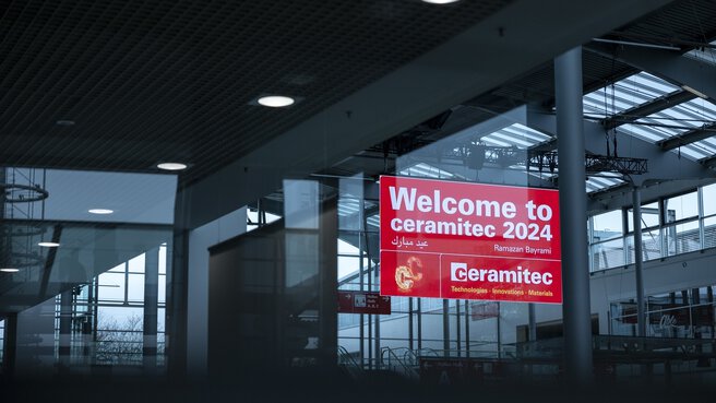 Abgedunkelte Ansicht einer Messehalle mit einem hervorgehobenen Hinweisschild mit der Aufschrift 