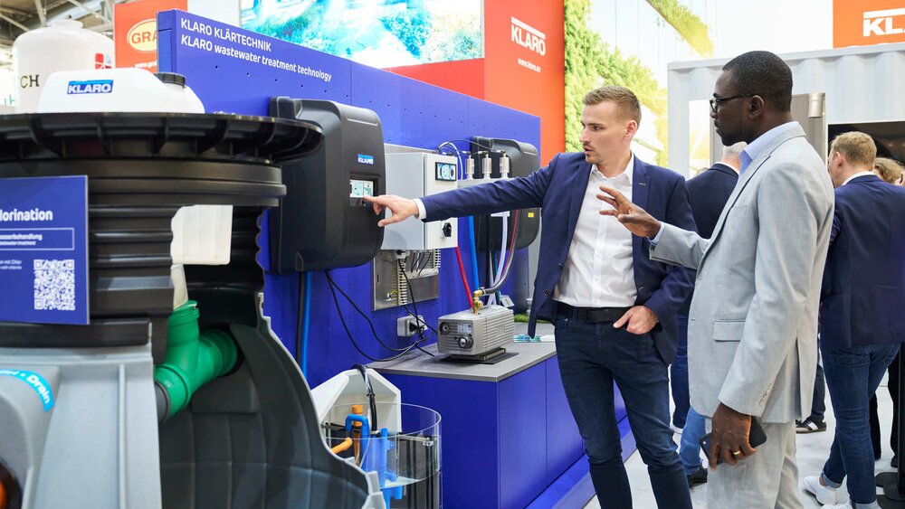 A consultant at the Klaro stand explains the digital control system of a wastewater treatment plant to a visitor.