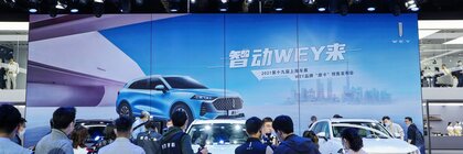 Menschen fotografieren und filmen neue WEY SUVs auf einer Autoshow, mit einem großen blauen Werbebildschirm hinter ihnen.