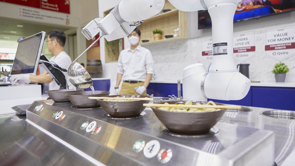 Robot arm autonomously filling bowls of pasta at an exhibition stand.
