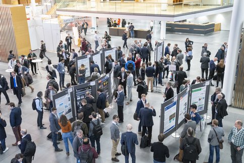 People gather at a LOPEC poster presentation, discussing and looking at the scientific posters.