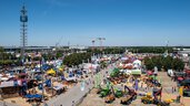 Aerial view of the open-air grounds of Messe München during INTERFORST. People bustle between colourful exhibition stands and forestry machinery.